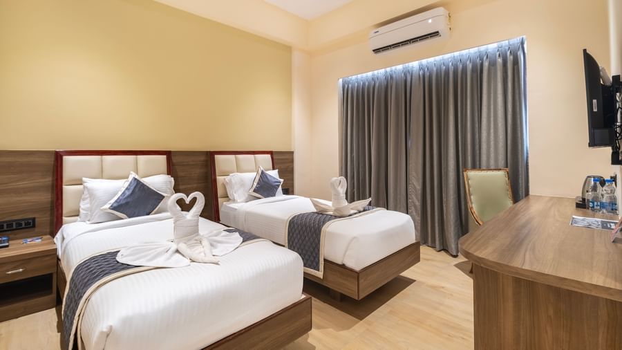Twin bed room at Monday Hotels Amalapuram Heights with window and air-conditioning.