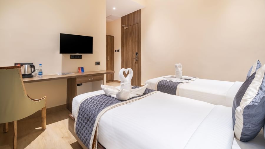 Twin bed room at Monday Hotels Amalapuram Heights with modern amenities.