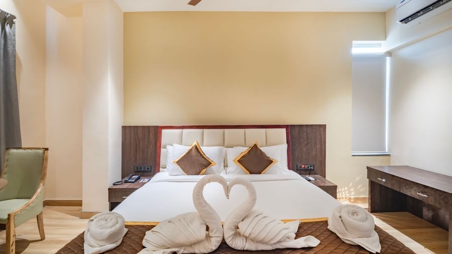 Deluxe room at Monday Hotels Amalapuram Heights with swan towel decor on bed.