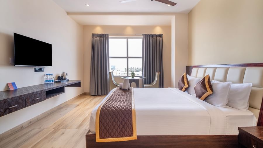 Spacious room at Monday Hotels Amalapuram Heights with king size bed, TV, ceiling fan, and seating area.