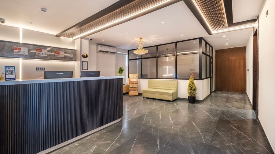Well-lit hotel reception with modern interiors, seating area, and plant decoration at Monday Hotels Amalapuram Heights