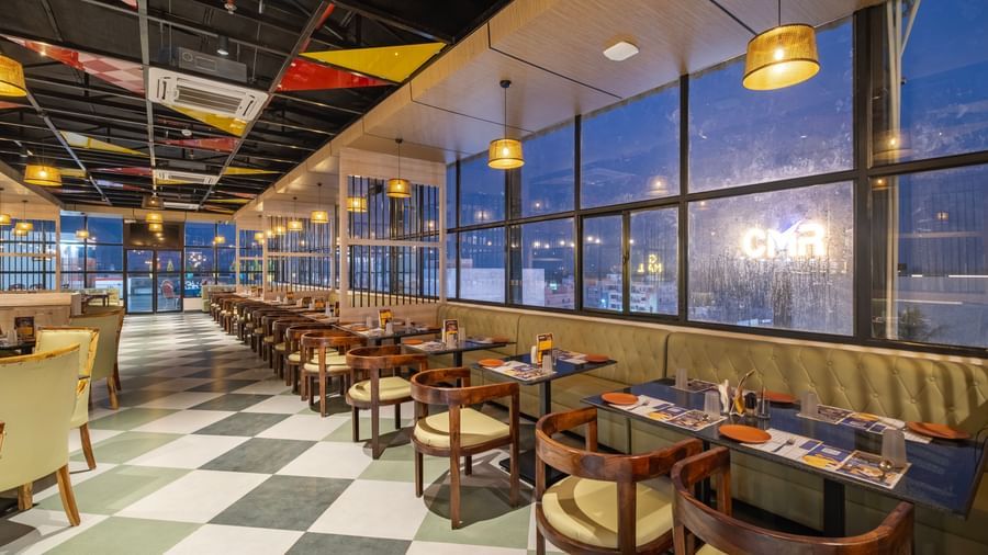Bright dining hall at Monday Hotels Amalapuram Heights with large glass windows.