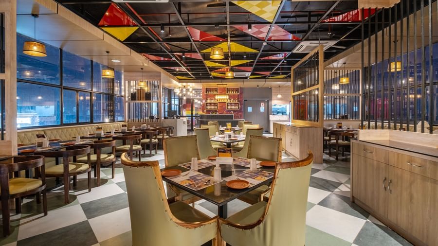Dining space at Monday Hotels Amalapuram Heights with elegant seating, colourful seating, and city views.