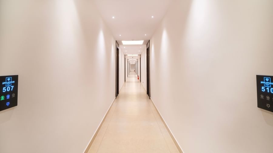 Bright corridor with modern lighting and white painted wall at Monday Hotels Amalapuram Heights.