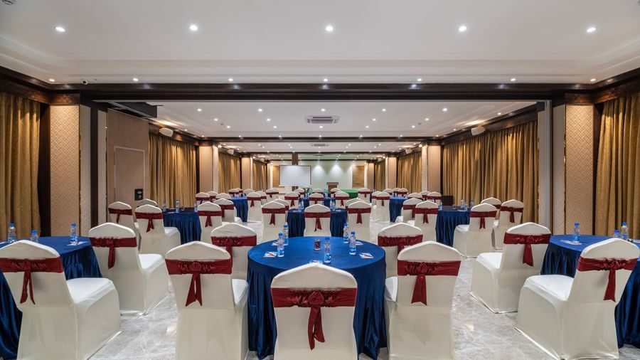 Back view of an event space at Monday Hotels Amalapuram Heights decorated with covered chairs.