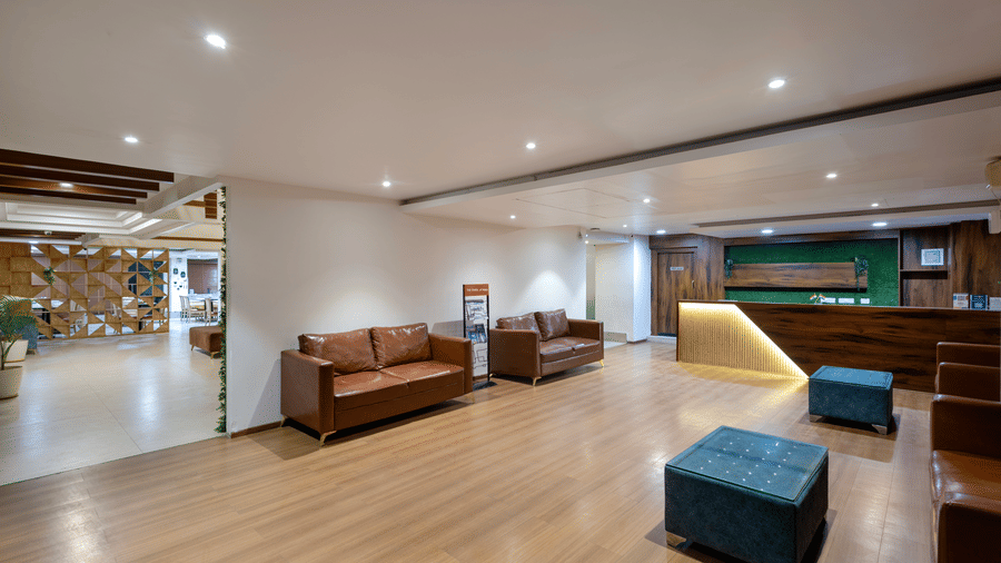 Spacious living area in the Superior King Room at Monday Hotels HITEC City Hyderabad featuring modern seating, warm lighting, wooden flooring and contemporary interiors.
