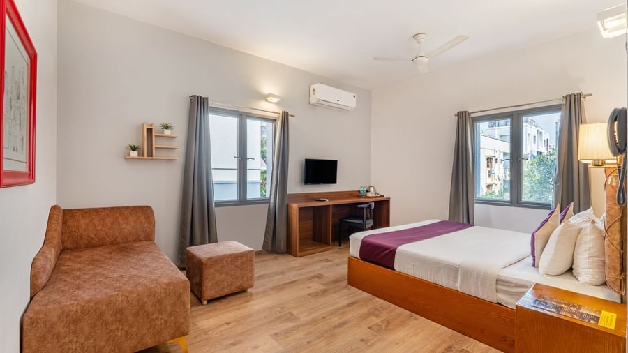 A hotel room with a bed, a seating area, and a wall mounted tv – Monday Hotels HITEC City, Hyderabad