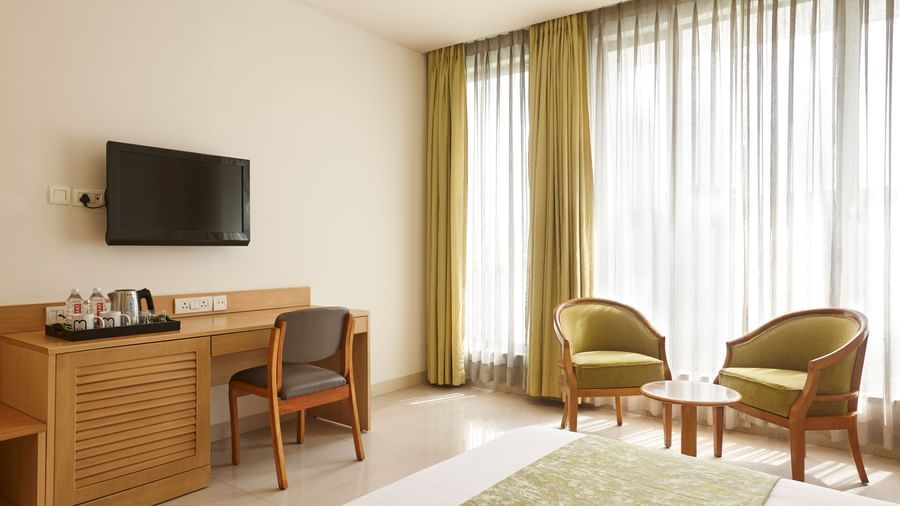 A hotel room at Monday Hotels Mahape, Navi Mumbai, featuring a bed, a TV, and a seating area.