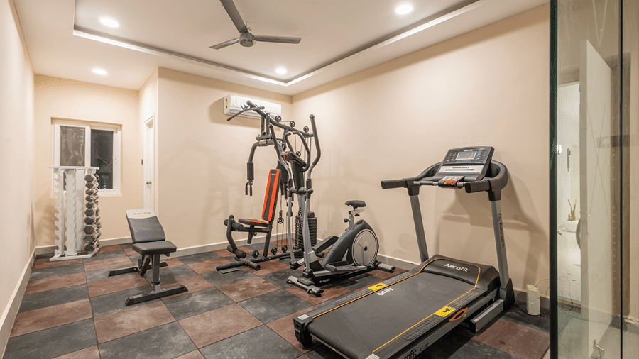 Fitness centre with a treadmill, elliptical trainer, multi-gym station, bench and dumbbell rack at Monday Hotels & Suites Madhapur, Hyderabad.