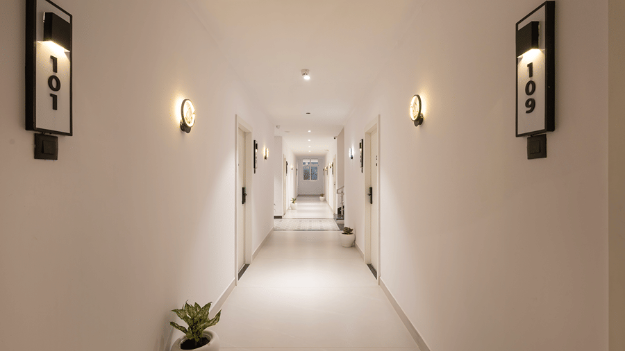 Guest corridor with illuminated room number signs 101 and 109, wall lights and a potted plant at Monday Hotels & Suites Madhapur, Hyderabad.