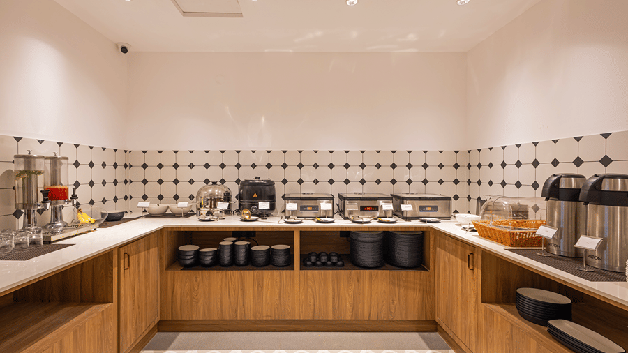 U-shaped breakfast buffet counter with chafing dishes, juice dispensers, flasks and crockery at M-Salt at Monday Hotels & Suites Madhapur, Hyderabad.