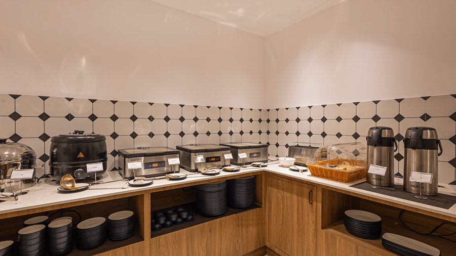 Breakfast buffet counter with a soup kettle, chafing dishes, bread basket, flasks and stacked crockery at M-Salt at Monday Hotels & Suites Madhapur, Hyderabad.