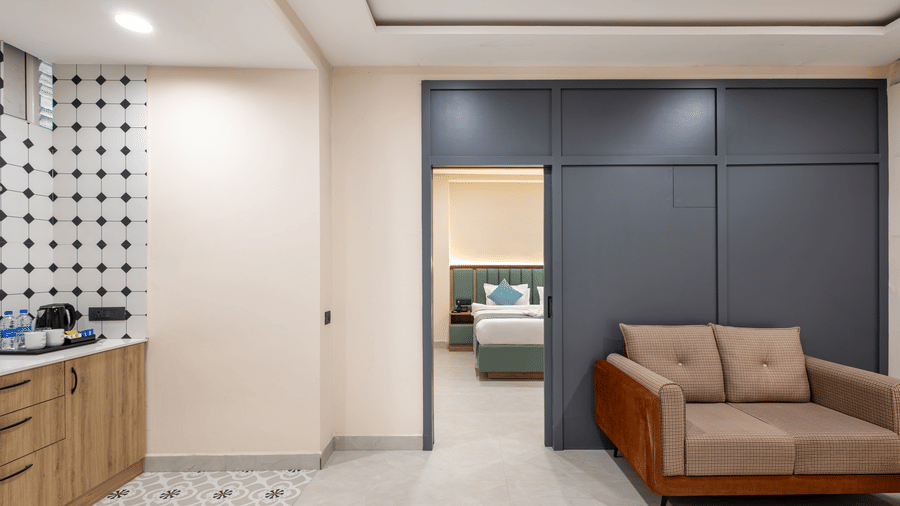 A suite area with a couch, a sliding door leading to an inner bedroom, and a kitchenette counter at Monday Hotels & Suites Madhapur Hyderabad.