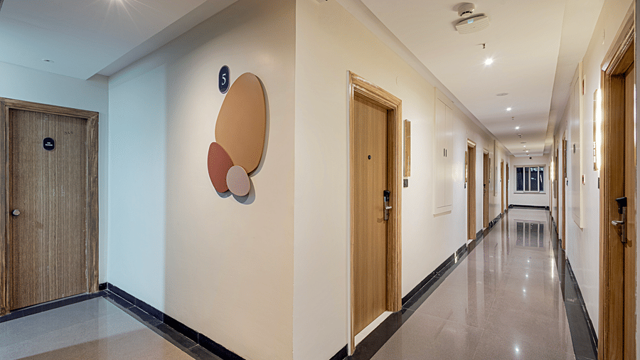 The lobby at Monday Premium, Madhapur, featuring an elongated hallway with several doors, and a wall-art.