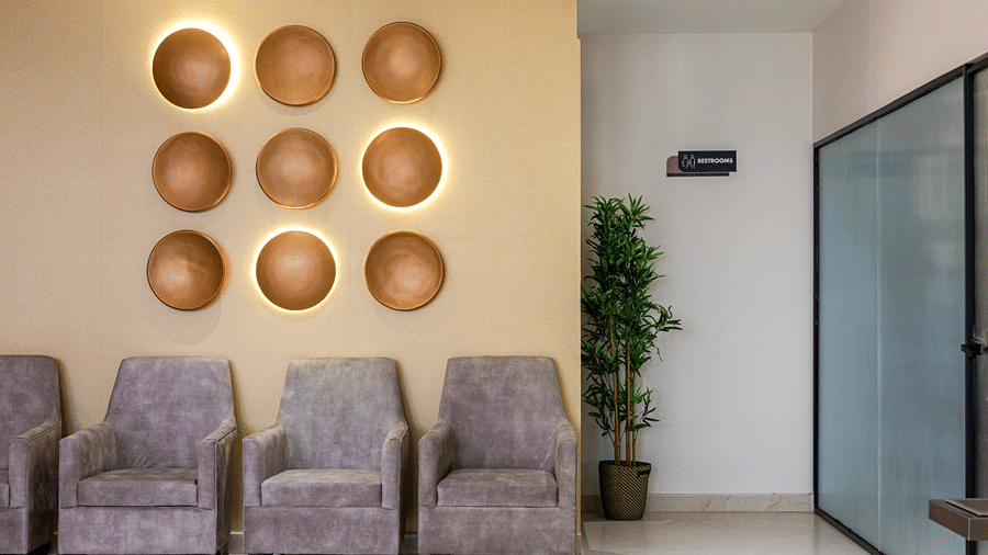 The reception at Monday Premium, Madhapur, featuring cushions, a plant, wall decorations, and a door.