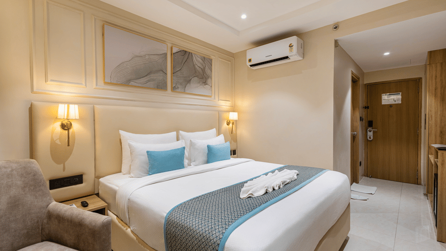 A room at Monday Premium, Madhapur, featuring a large bed, bedspreads, pillows, windows, a cushion, a door, and a wall mounted air-conditioner.