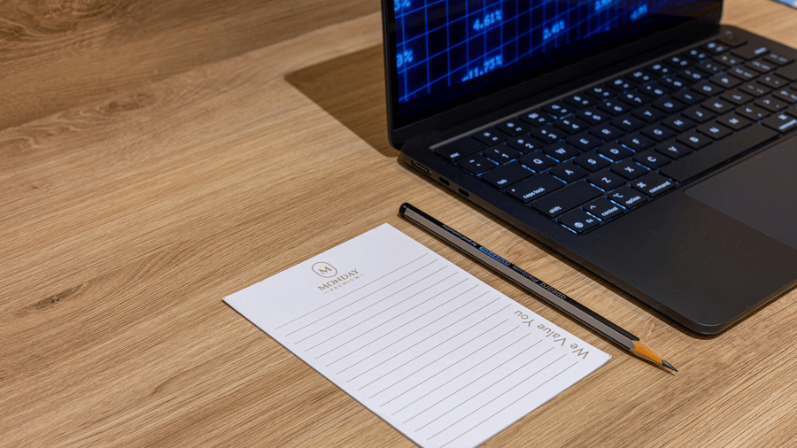 A work desk at the rooms of Monday Premium, Madhapur, with a laptop, a pencil, and a sheet of paper on the table.
