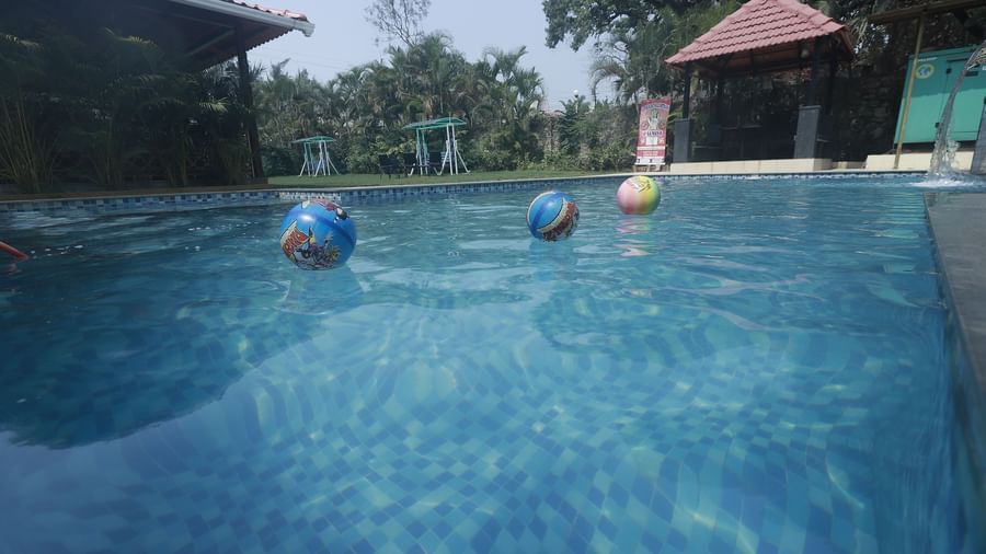 Poolside view with floating colourful beach balls, trees, and a gazebo at Mountview Resort.