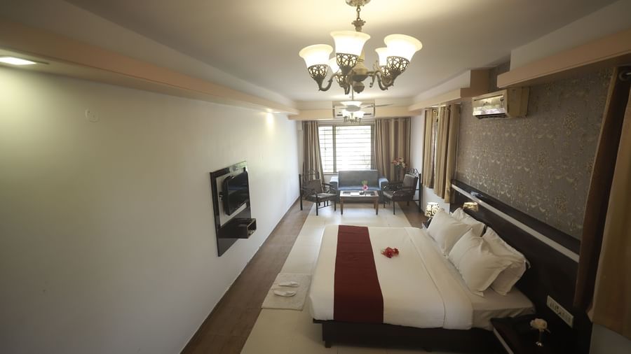 Side view of the Deluxe Room at Mountview Resort, which features a king size bed, a bedside table, wall-mounted TV, and curtains drawn.