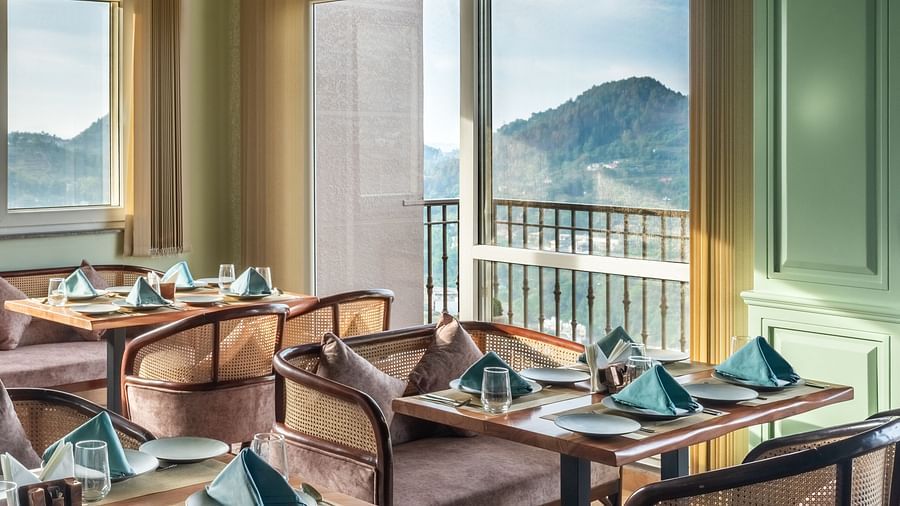 an image of a dining space filled with natural light, chairs and tables are placed with cutlery and hand towels at Mountoria Retreat, Naukuchiatal
