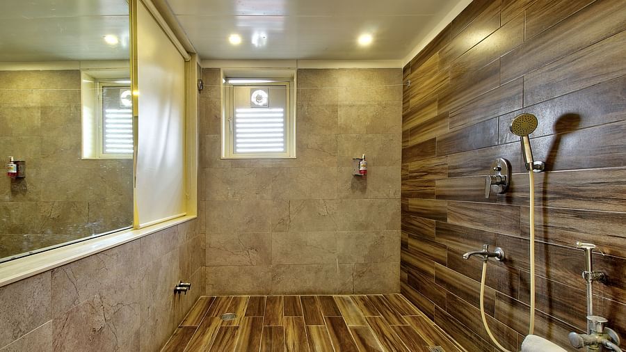 Walk-in shower with wooden and beige tiles, overhead and hand-held showerheads, and a frosted window.
