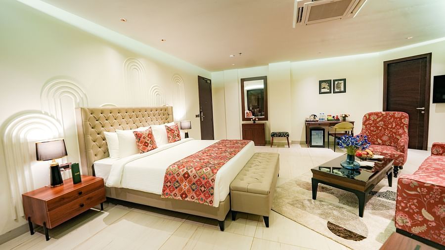 A large suite in Bankhandi featuring a queen size bed with a bed bench, a night stand with a lamp, and cosy furniture - NAMAMI BY ZENQ BANKHANDI