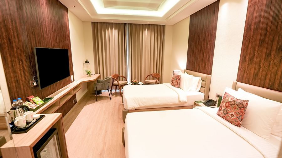 An image of a room in Bankhandi with twin beds, a minibar, a wall-mounted television and chairs - NAMAMI BY ZENQ BANKHANDI