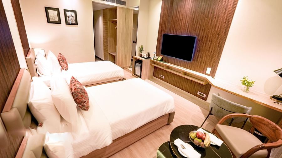 A hotel room with twin beds, a wall-mounted television, a coffee table and a cushioned chair - NAMAMI BY ZENQ BANKHANDI