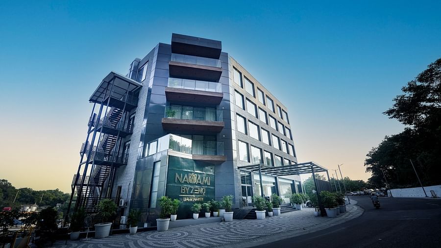 A twilight scene featuring a hotel structure with expansive windows and a sign displaying the name of the hotel - NAMAMI BY ZENQ BANKHANDI