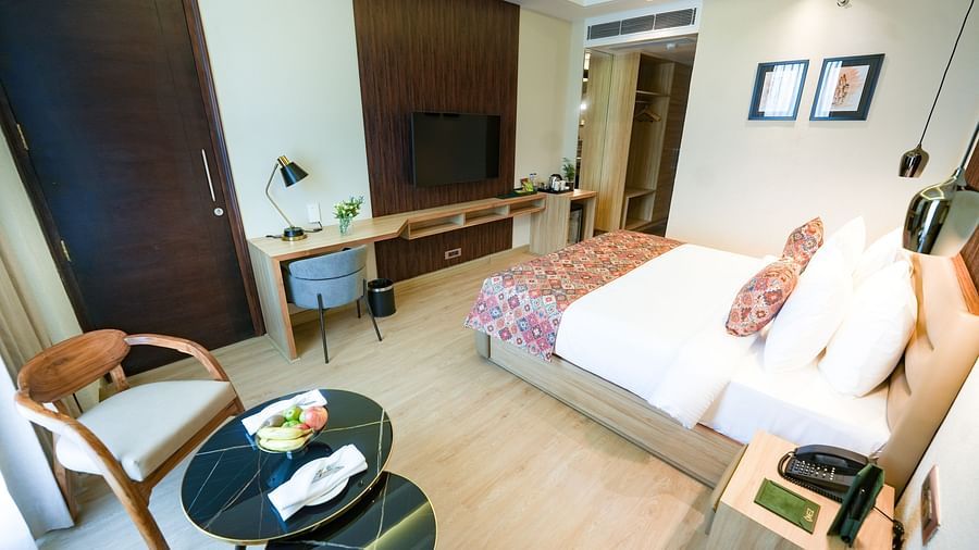 A view of our hotel room near Baglamukhi Temple with a large bed, a work desk and a coffee table surrounded by chairs - NAMAMI BY ZENQ BANKHANDI