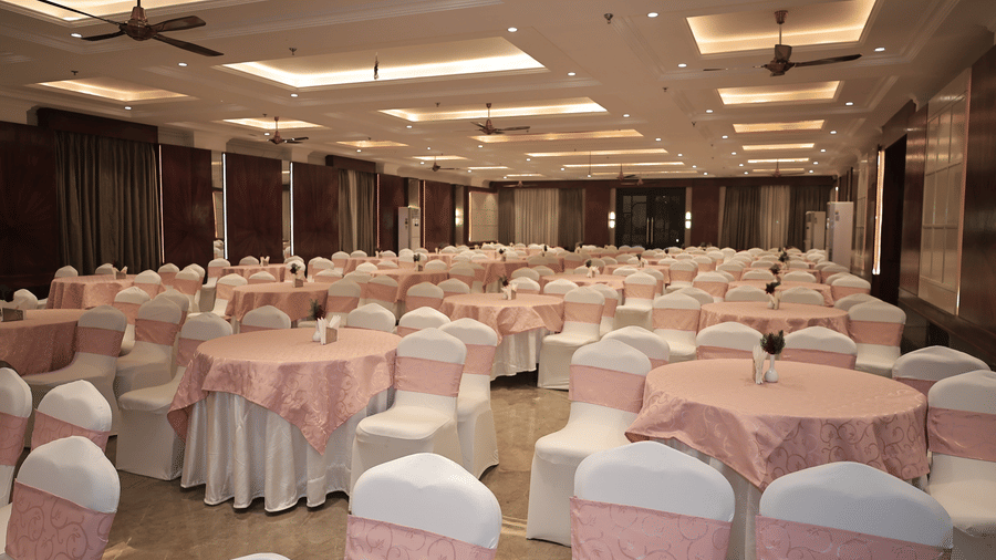 Large indoor banquet venue arranged with decorated round tables and chairs, ideal for weddings and conferences.