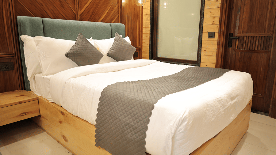 Spacious presidential suite bedroom with a king size bed, elegant wooden interiors, warm lighting, and modern decor.