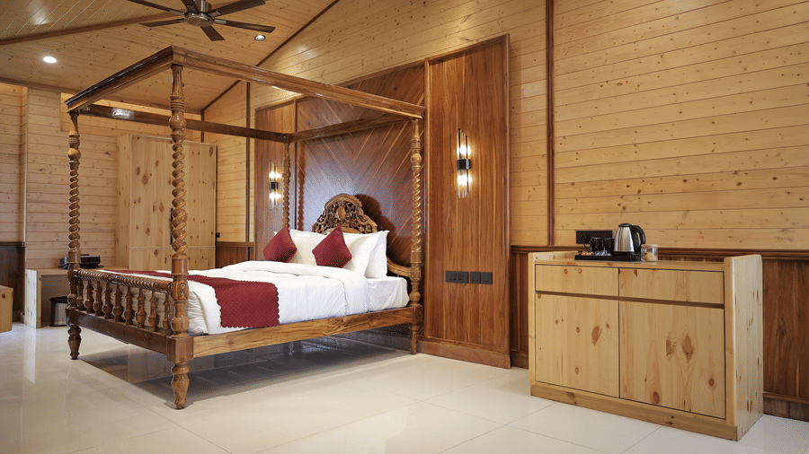 Spacious Bliss Bloom Suite bedroom with wooden interiors, king bed, and elegant lighting.
