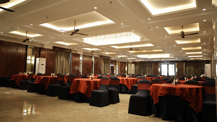 Interior view of a sophisticated event space with wood-panelled walls, coffered ceilings, and multiple rows of formal seating.