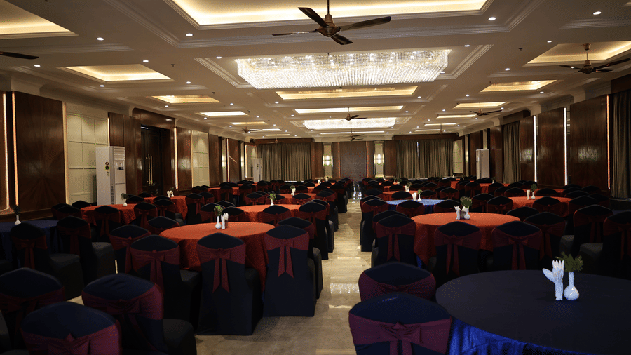 Spacious conference room set up for a banquet, showing polished floors and warm lighting from recessed ceiling panels.