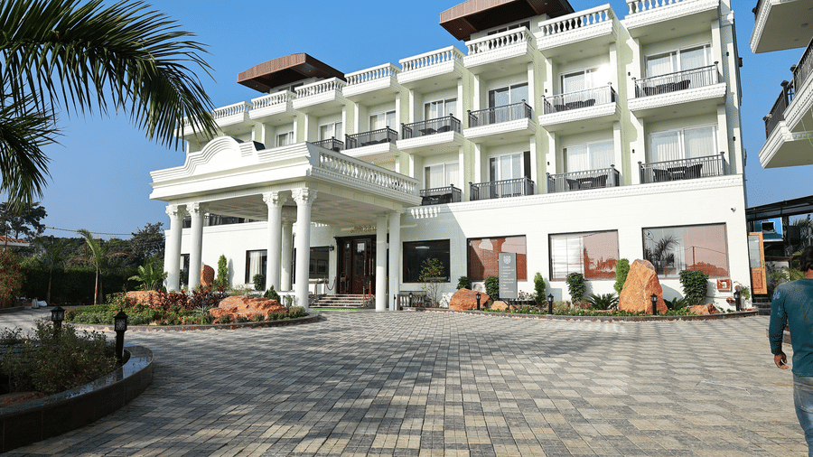 Cobblestone driveway leading to a grand white hotel entrance with tall pillars and manicured landscaping.