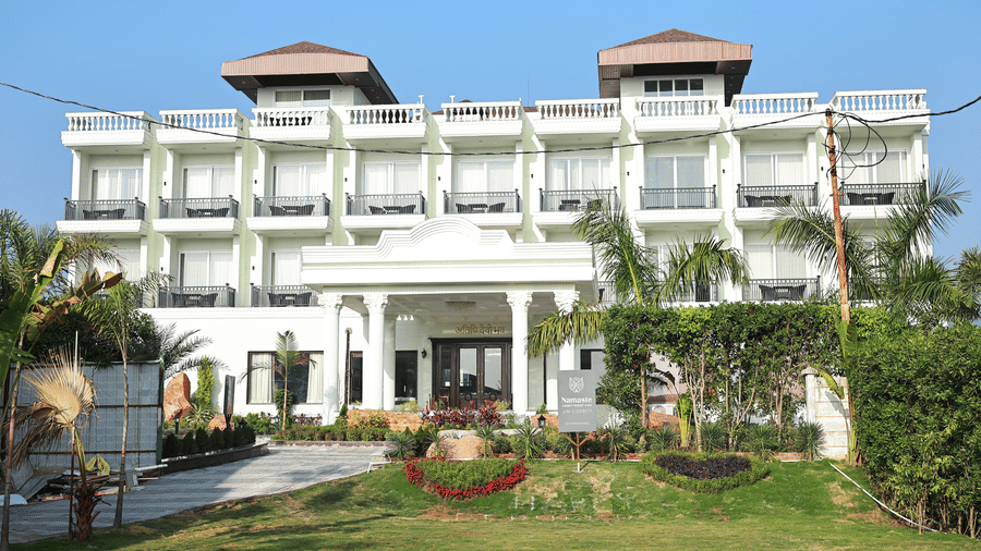 Front view of a white three-story hotel with balconies and a grand entrance.