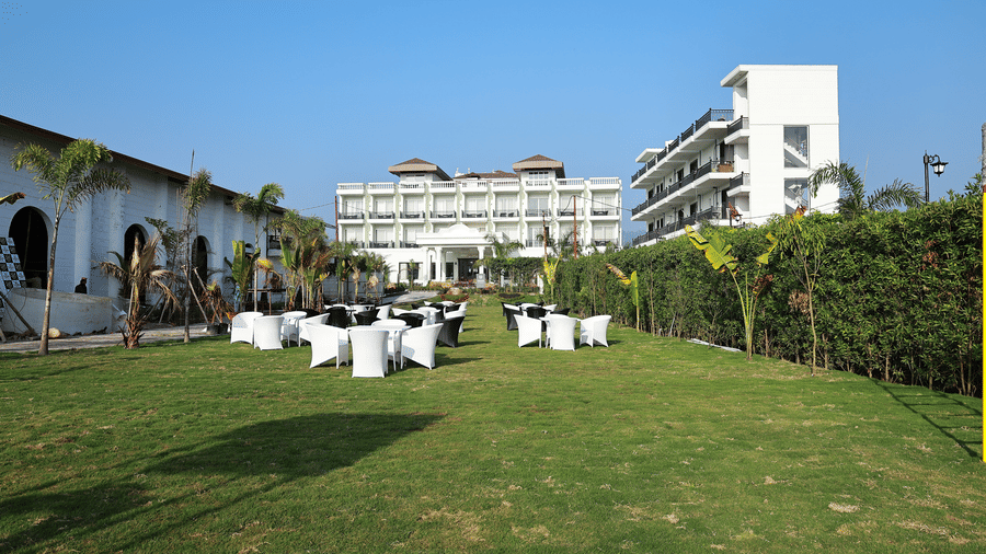 A spacious outdoor event area featuring rows of black and white seating clusters on a green field.