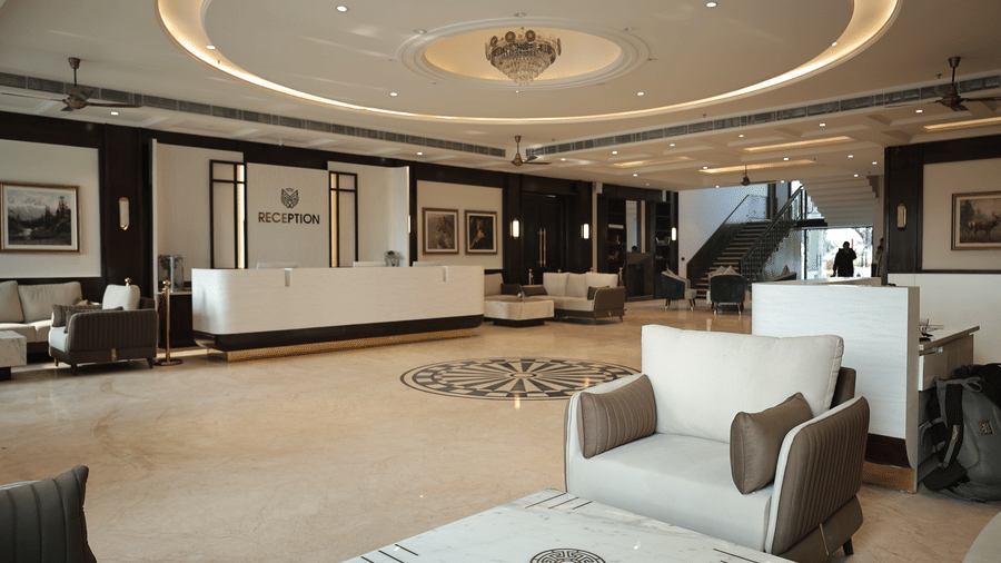 Spacious hotel lobby with reception desk, chandelier ceiling design, marble flooring, and comfortable seating area.