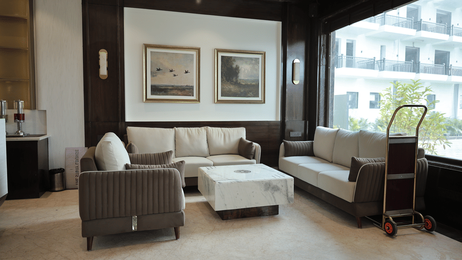 Comfortable hotel lounge seating near large windows featuring sofas, marble coffee table, and soft natural lighting.