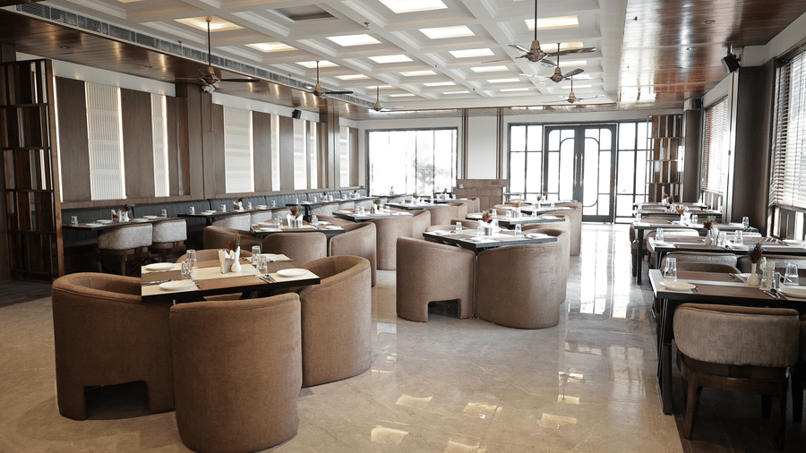 Spacious restaurant dining area with comfortable seating, polished floors, and large windows allowing natural light inside.