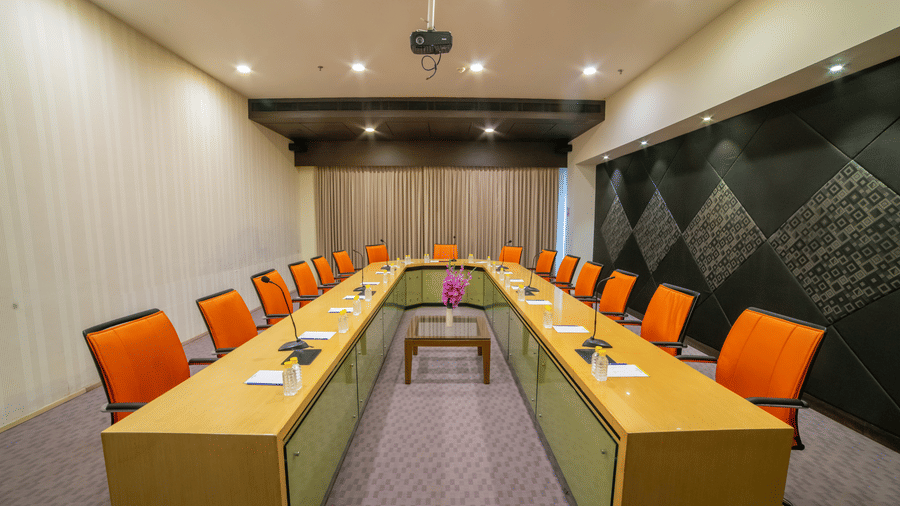 Boardroom with U-shaped table, modern decor, and bright orange chairs at Narayani Heights Hotel & Resorts, Ahmedabad.