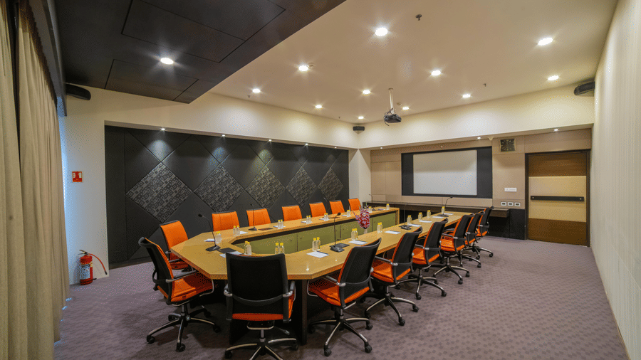Conference room with a long table, orange chairs, and presentation screen at Narayani Heights Hotel & Resorts, Ahmedabad.