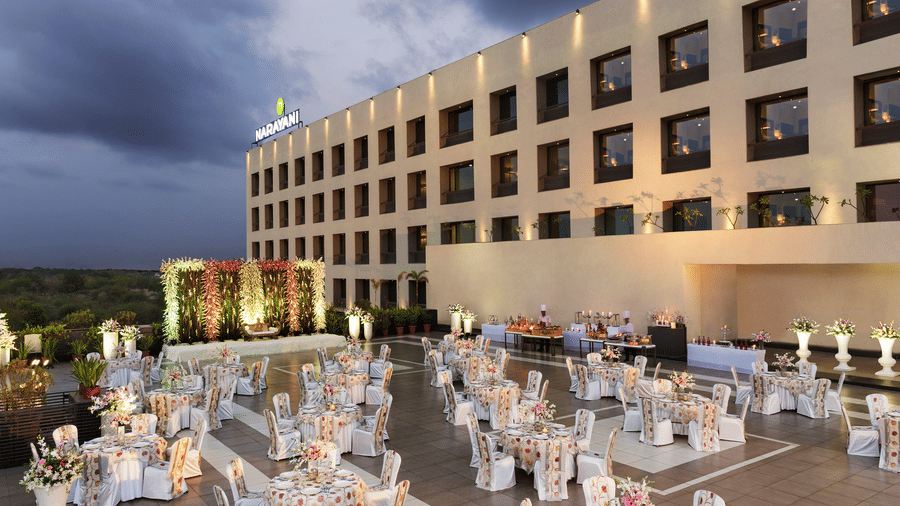 Outdoor banquet setup with white chairs and tables at Narayani Heights Hotel & Resorts, Ahmedabad.