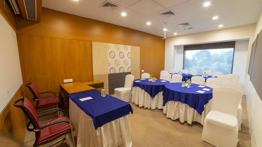 Small conference room with round tables covered in blue and white linens - Narayani Heights Hotel & Resorts