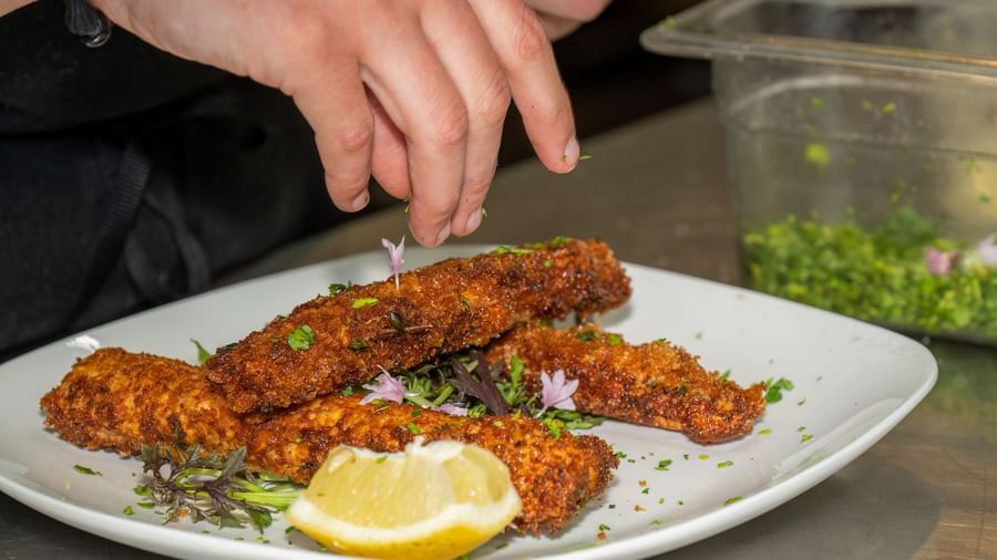 A chef plates golden-brown croquettes with lemon garnish and herbs at Narrow Gauge Inn.