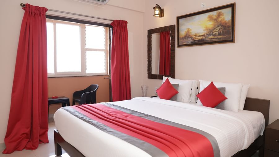 A bed placed near a window with curtains, wall art, bedside tables at Nazri The Verda Hotel, Arambol.