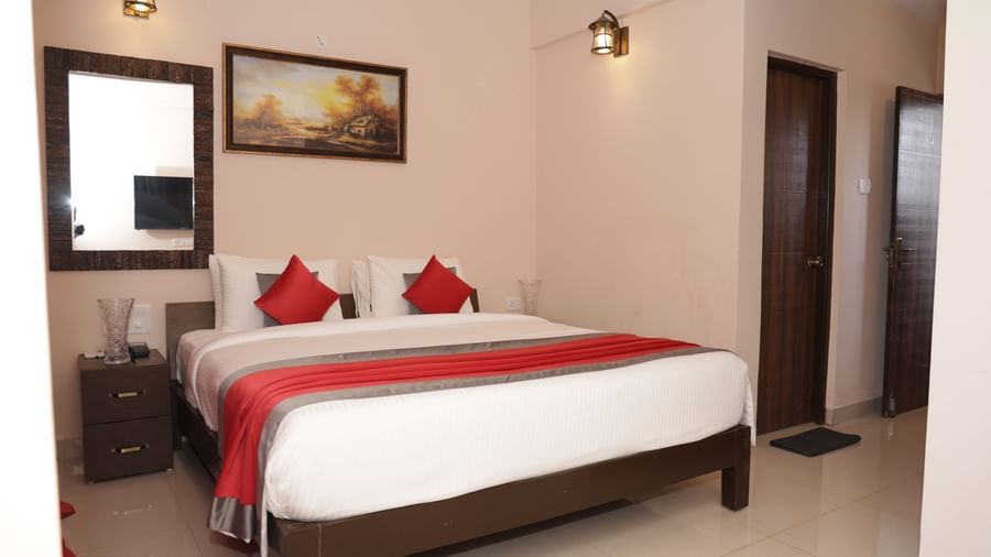 A bed with 2 bedside tables, lamps, wall art and an attached bathroom at Nazri The Verda Hotel, Arambol.