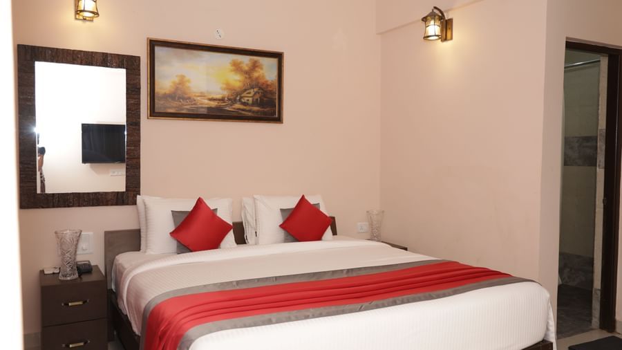 A bed with pillows, bedside tables, wall art and a mirror at Nazri The Verda Hotel, Arambol.