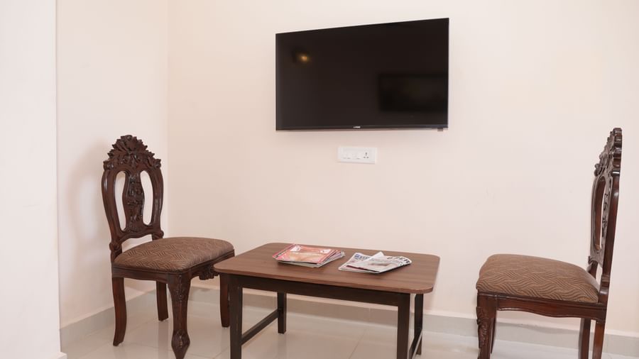 A wall-mounted television with 2 chairs and a table beneath at Nazri The Verda Hotel, Arambol.